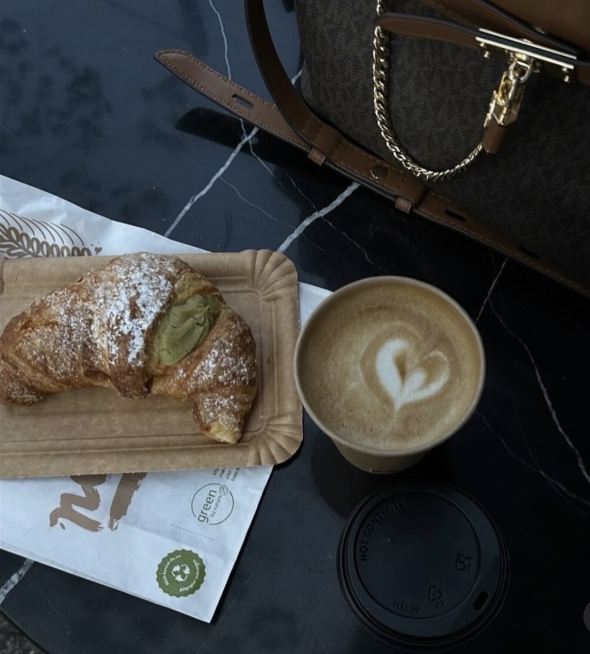 Croissant und Kaffee auf dunklem Marmortisch